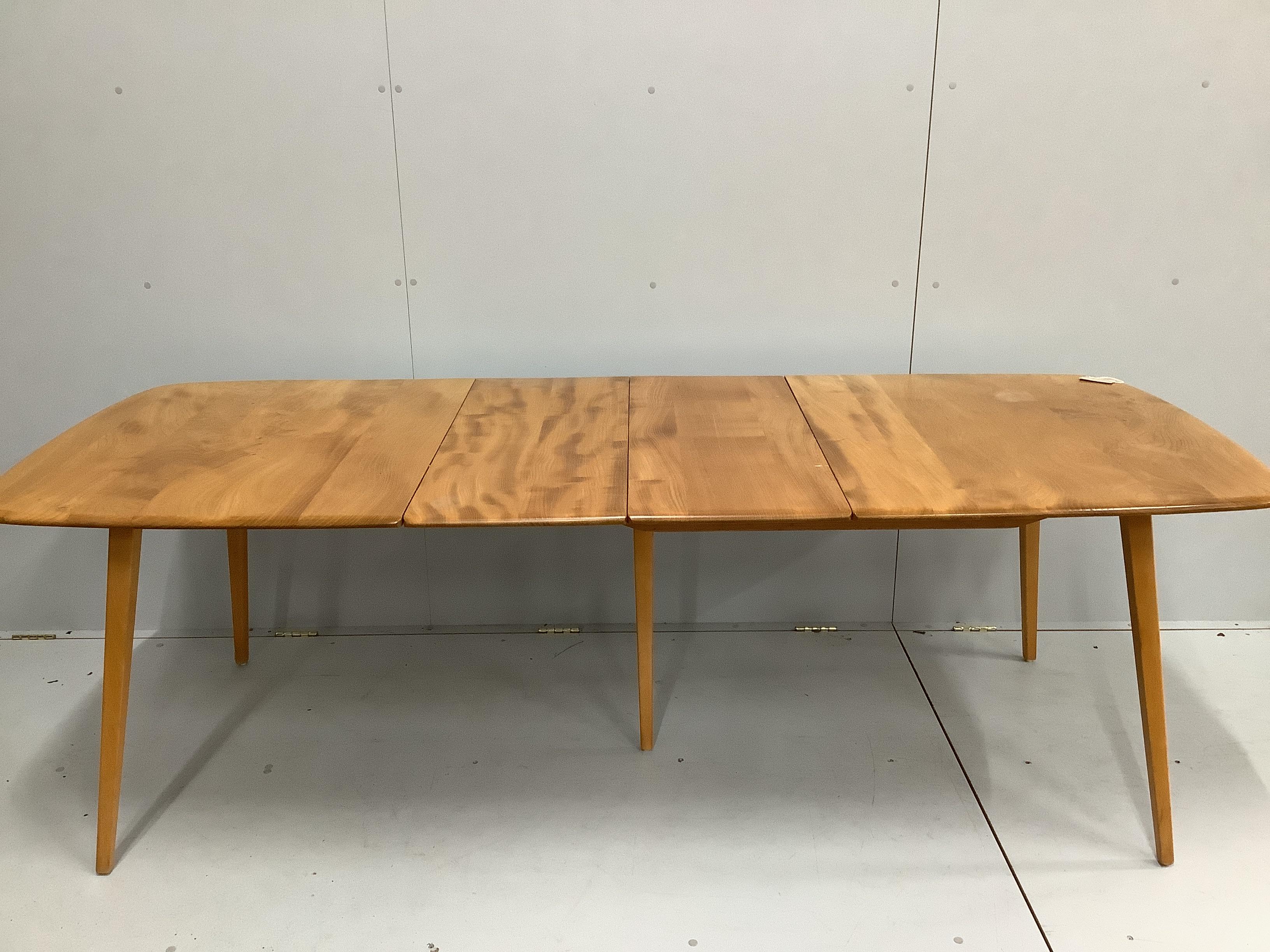 An Ercol elm and beech rectangular extending dining table, 224cm extended, width 88cm, height 71cm together with four Ercol elm and beech comb back dining chairs